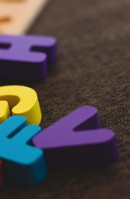 Lettere colorate sopra una tavola di legno di un gioco per imparare l’alfabeto