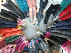 Foto vista dall'alto dei piedi di un gruppo di bambini disposti in cerchio che indossano calzini spaiati.